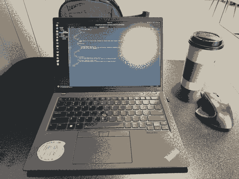 A ThinkPad sitting on a desk with a coffee cup next to it