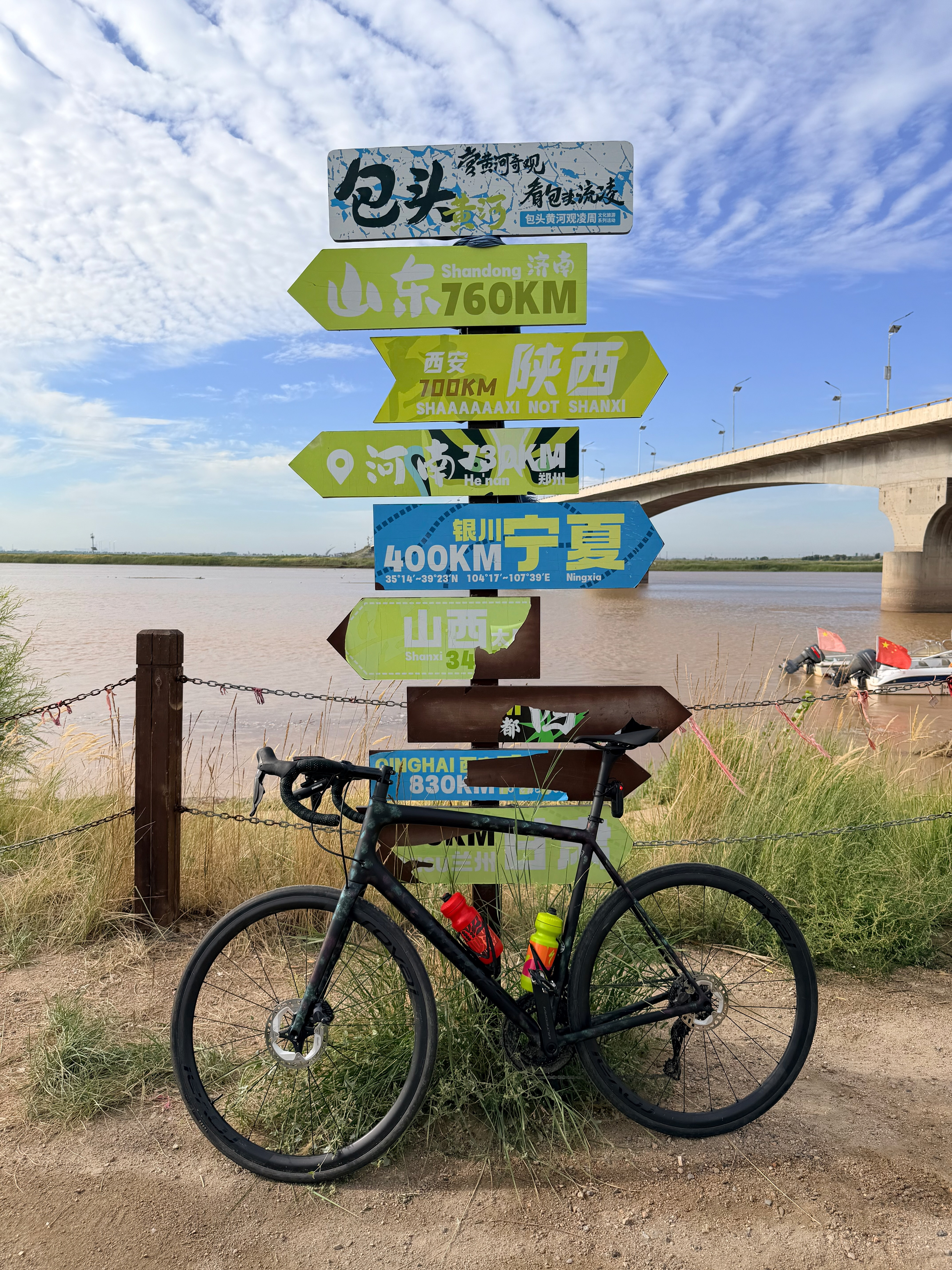 A bike leaning against a sign in front of a river