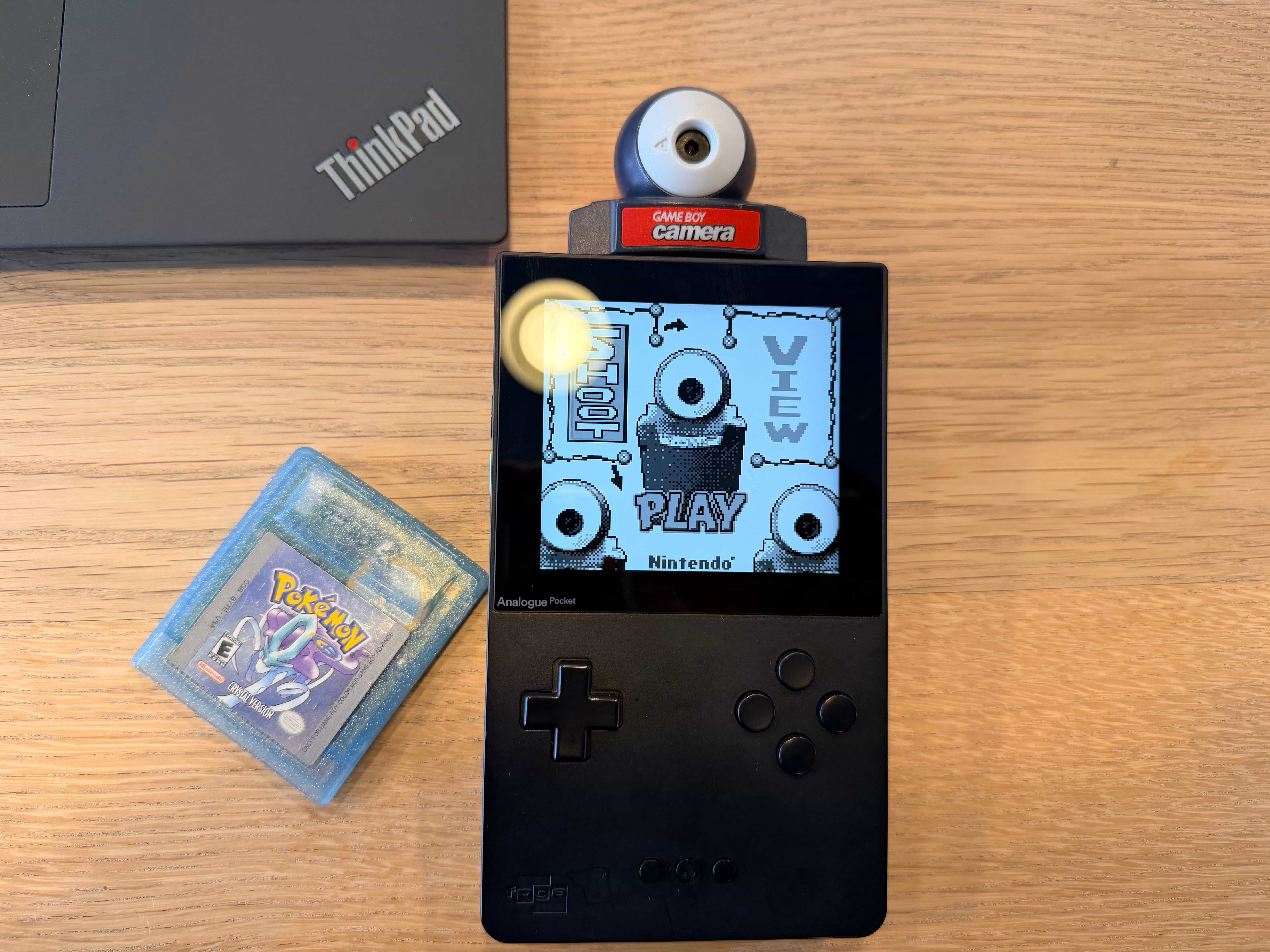 An Analogue Pocket with a Gameboy Camera cartridge next to a ThinkPad