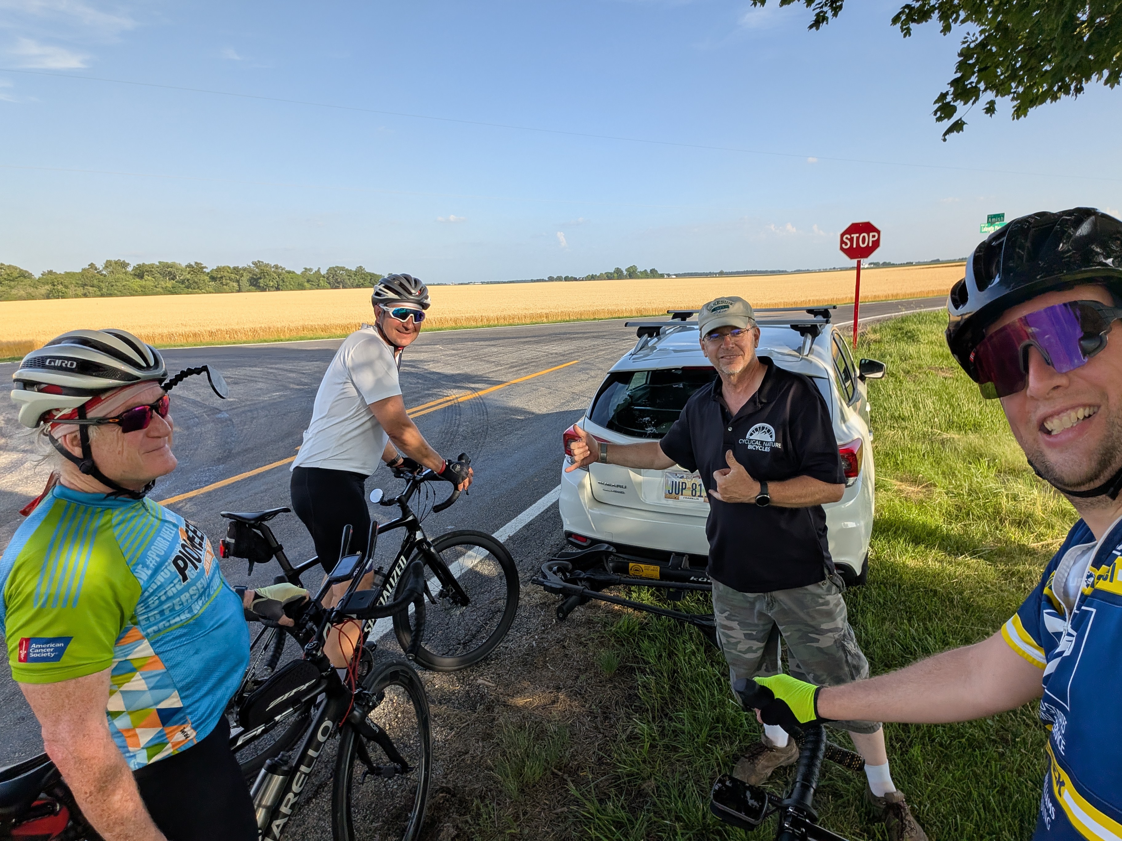 Cyclists standing around a car on a hot day